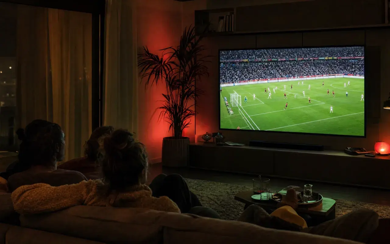 Salotto italiano scuro con un grande televisore che trasmette una partita di calcio in diretta, illustrando il calcio incluso in una liste IPTV funzionante